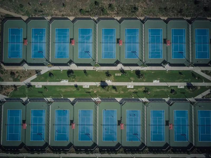 Drone view showcasing aligned tennis courts with clear pathways and greenery