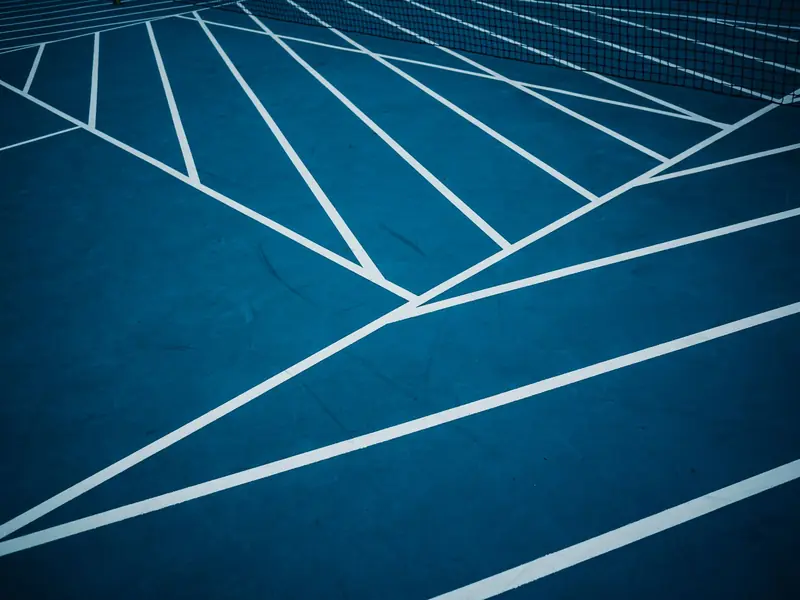 Blue tennis court with abstract white lines creating geometric patterns