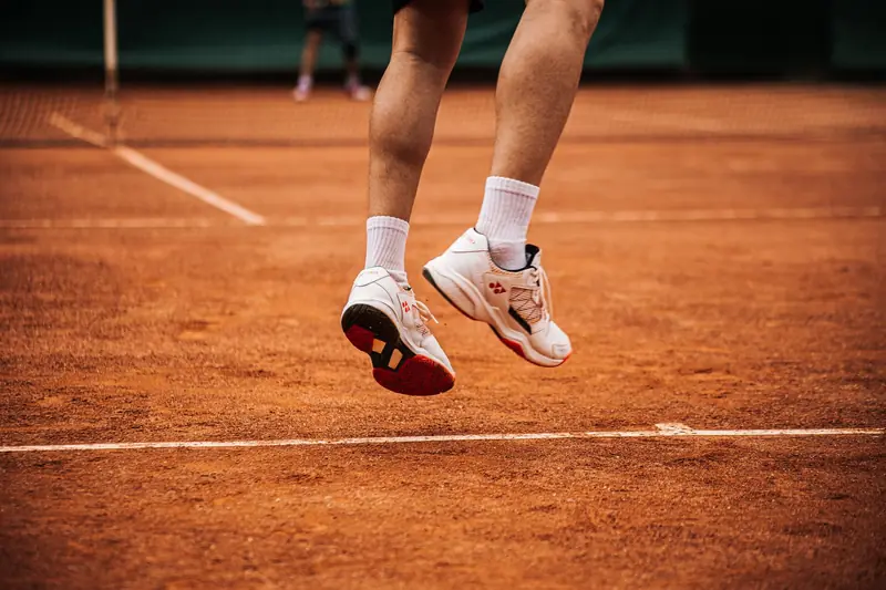 Low angle view of a tennis player jumping on a clay court, showcasing movement