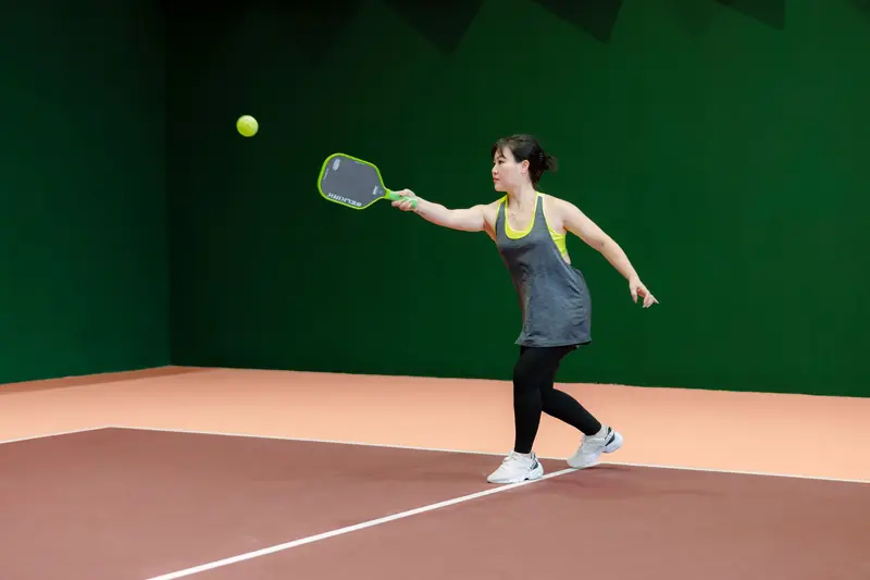 A woman engaging in pickleball on an indoor court, showcasing athletic skill and focus