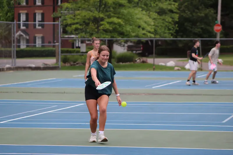 Group of young adults playing pickleball on an outdoor court in Ohio, capturing the spirit of fun and athleticism
