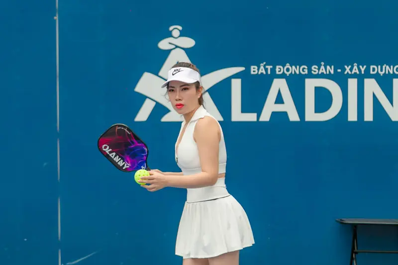 Dynamic image of a female pickleball player ready to serve during a match in Hải Phòng, Vietnam